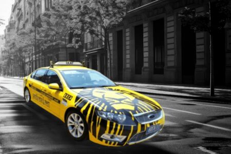 Yellow taxi with a lion printed on the hood.