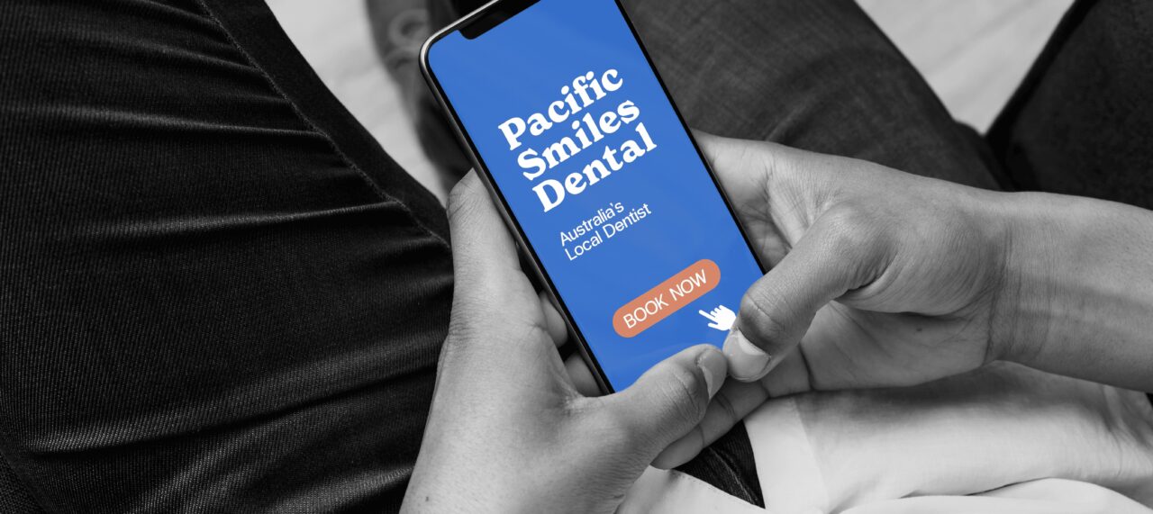 A person sitting down and using both hands to hold their phone.