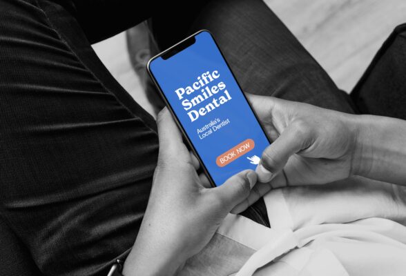 A person sitting down and using both hands to hold their phone.